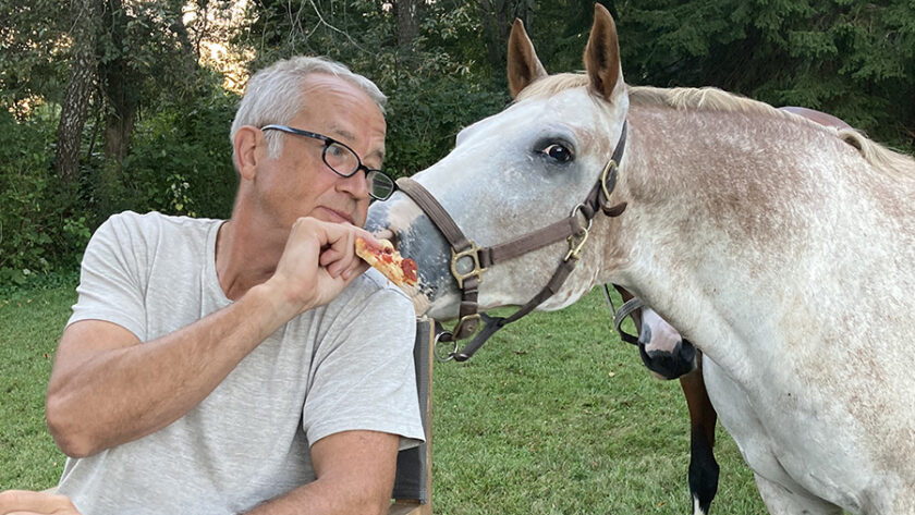 Buck feeding Brody a slice of pizza